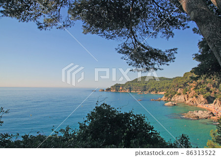 Santa Clotilde gardens. Beautiful sea view of Boadella beach through the green trees. Lloret de Mar, Costa Brava, Catalonia, Spain. Santa Clotilde gardens. Beautiful sea view of Boadella beach through the green trees. Lloret de Mar, Costa Brava, Catalonia, Spain. 86313522