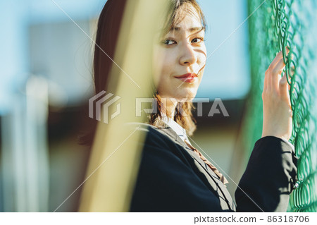 High school girl standing on the fence side 86318706