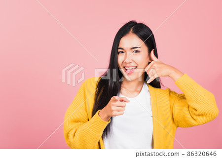 woman smiling doing phone gesture with hand fingers on telephone and pointing 86320646