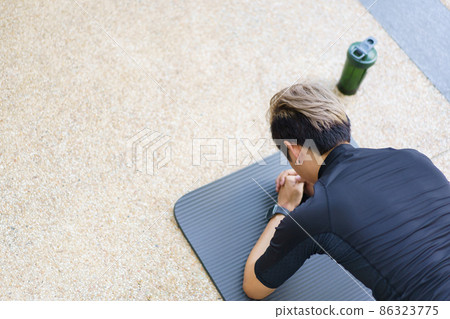Active Asian young man making an outdoor body weight exercise close up, sportsman doing body weight workout by pushup and plank. Asian sportsman exercising for muscle and body building. 86323775