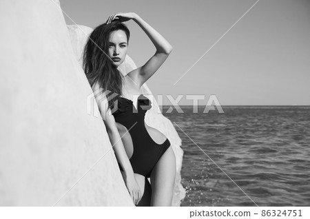 Beautiful elegant lady poses on the beach in black swimming suit Beautiful elegant lady poses on the beach in black swimming suit 86324751