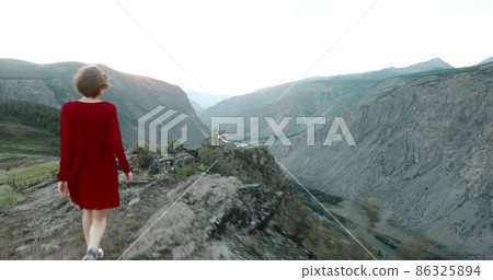 Elegant young lady in a red dress on a mountain 86325894
