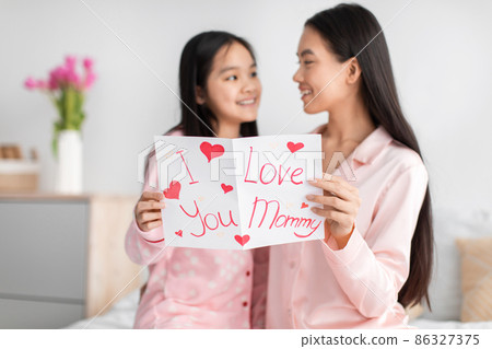 Satisfied happy korean young girl and millennial female read card and congratulate with mother day, sit on bed Satisfied happy korean young girl and millennial female read card and congratulate with mother day, sit on bed 86327375