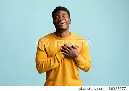 Religious young black man praying on blue Religious young black man praying on blue 86327377