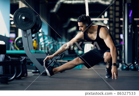 Handsome Young Middle Eastern Male Athlete Warming Up Before Training At Gym Handsome Young Middle Eastern Male Athlete Warming Up Before Training At Gym 86327533
