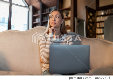 Pensive woman working on laptop at home 86327691