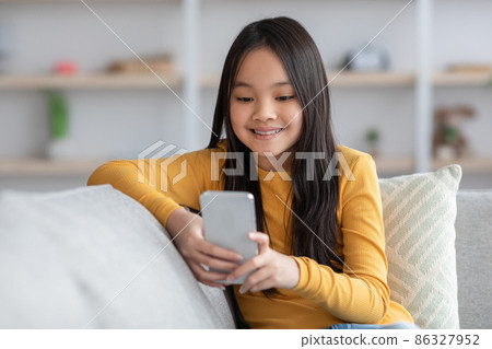 Cute asian girl schooler playing games on cellphone, panorama 86327952