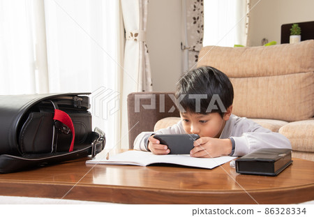 Elementary school boy looking at a smartphone while studying 86328334