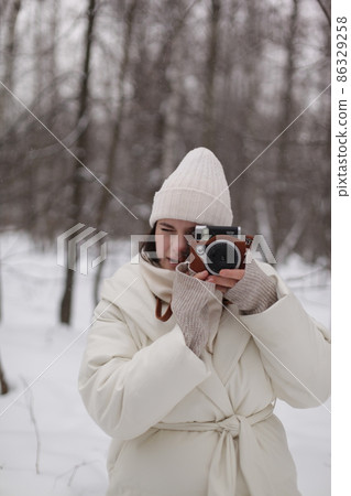 a girl with a camera on a winter walk in the woods a girl with a camera on a winter walk in the woods 86329258