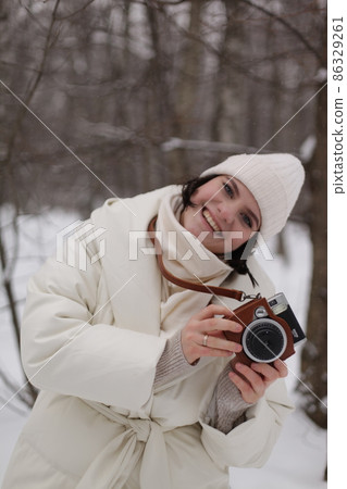 a girl with a camera on a winter walk in the woods a girl with a camera on a winter walk in the woods 86329261