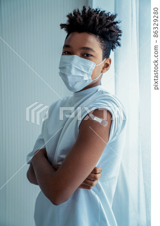 African American teenager showing COVID-19 vaccine bandage merrily 86329280
