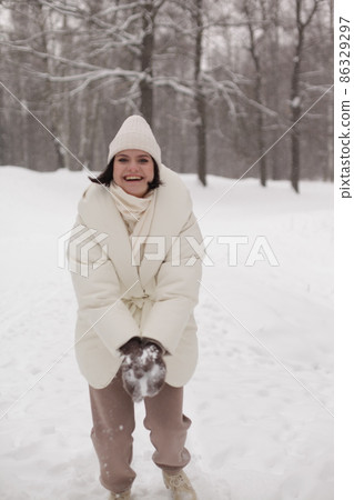 Two girls playing snowballs in the snow in the winter in a warm winter clothes Two girls playing snowballs in the snow in the winter in a warm winter clothes 86329297