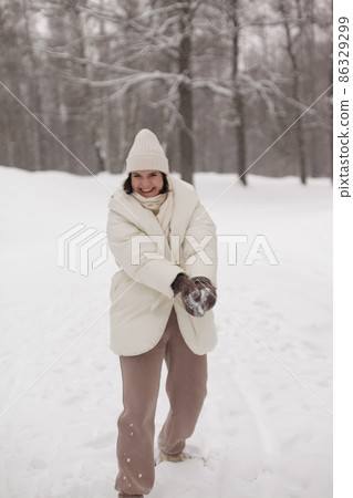Two girls playing snowballs in the snow in the winter in a warm winter clothes Two girls playing snowballs in the snow in the winter in a warm winter clothes 86329299