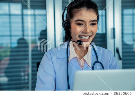 Doctor wearing headset talking actively on video call in hospital or clinic Doctor wearing headset talking actively on video call in hospital or clinic 86330665