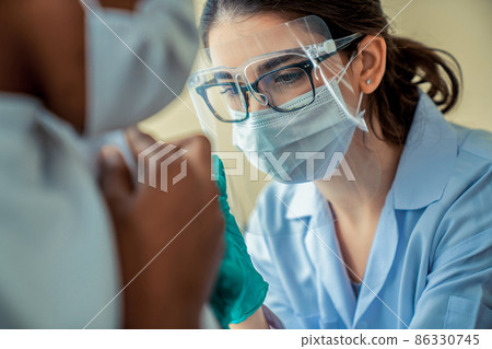 Young man visits skillful doctor at hospital for vaccination Young man visits skillful doctor at hospital for vaccination 86330745
