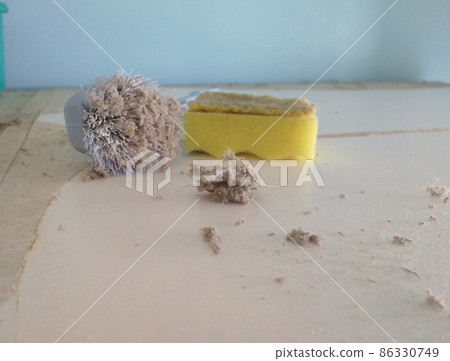 Cleaning dirty white surface with sponge and brush. Ball of common household dust. Cleaning dirty white surface with sponge and brush. Ball of common household dust. 86330749