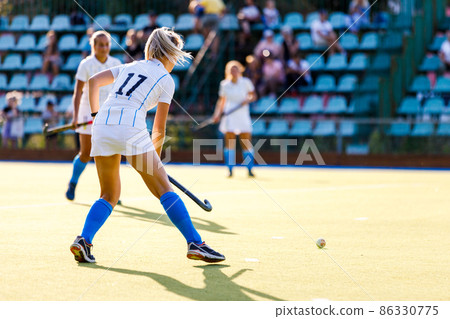 Young female field hockey player with the ball on the pitch Young female field hockey player with the ball on the pitch 86330775