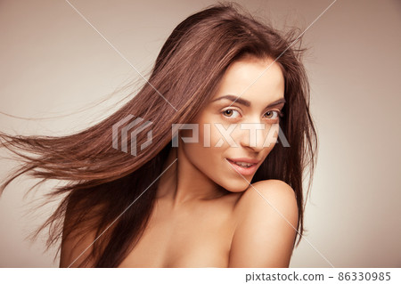 Attractive smiling woman with long hair on grey Attractive smiling woman with long hair on grey 86330985
