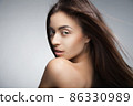 Attractive smiling woman with long hair on grey 86330989