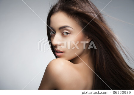 Attractive smiling woman with long hair on grey Attractive smiling woman with long hair on grey 86330989