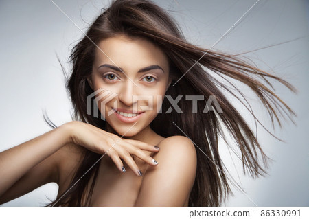 Attractive smiling woman with long hair on grey Attractive smiling woman with long hair on grey 86330991