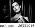 Beautiful young woman near a glass in interior 86331016