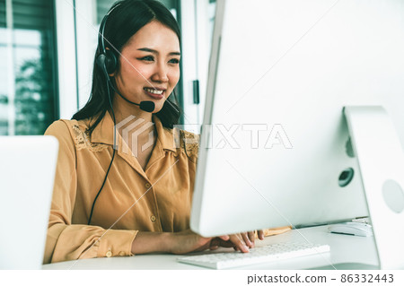 Businesswoman wearing headset working actively in office Businesswoman wearing headset working actively in office 86332443