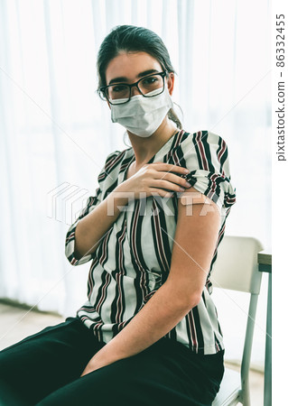 Young woman showing COVID-19 vaccine bandage merrily 86332455