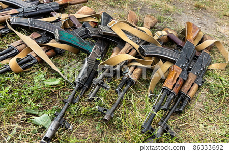 Military machine gun lies on the dry grass in the field 86333692