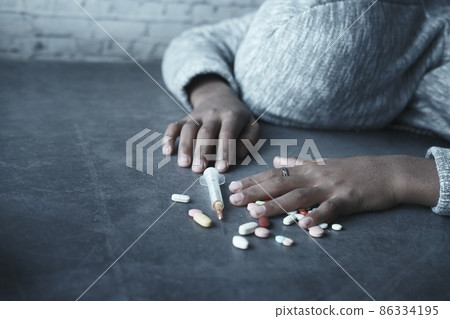 drug addiction concept with hand holding pills and syringe laying on floor drug addiction concept with hand holding pills and syringe laying on floor 86334195