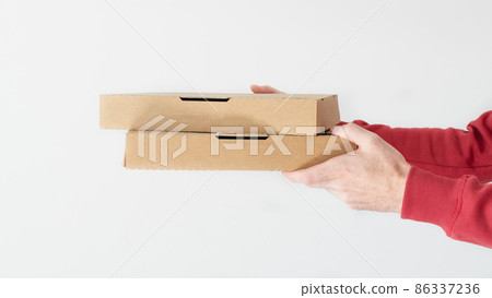 Courier hands holding cardboard pizza boxes over white background. Courier hands holding cardboard pizza boxes over white background. 86337236