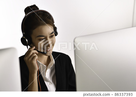 Asian woman call centre working use headset look at computer screen 86337393