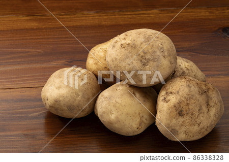 Potatoes lined up on a board Potatoes lined up on a board 86338328