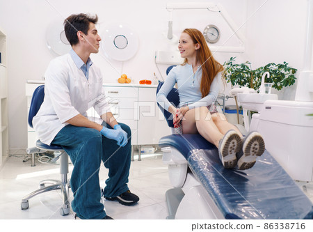 Ginger woman smiling and listening to male dentist explaining treatment during appointment in dental clinic 86338716