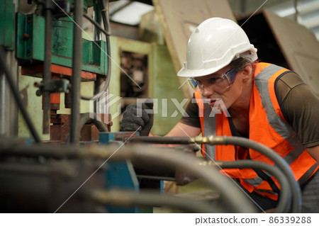 Professional engineer metalworker operating CNC milling machine center in manufacturing workshop 86339288