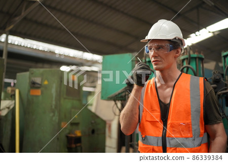 Professional engineer metalworker operating CNC milling machine center in manufacturing workshop 86339384