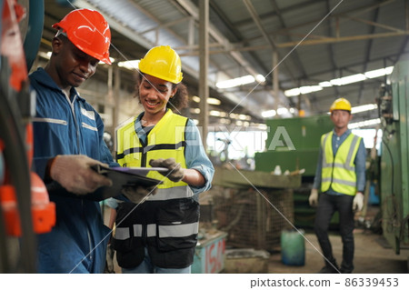 Male and Female Industrial Engineers Talk with Factory Worker on machine training. They Work at the Heavy Industry Manufacturing Facility. Male and Female Industrial Engineers Talk with Factory Worker on machine training. They Work at the Heavy Industry Manufacturing Facility. 86339453