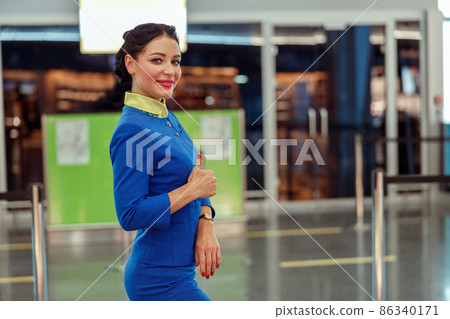Cheerful woman stewardess showing approval gesture at airport Cheerful woman stewardess showing approval gesture at airport 86340171