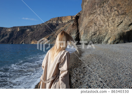 a young beautiful woman runs along a pebble beach against the backdrop of sea a young beautiful woman runs along a pebble beach against the backdrop of sea 86340330