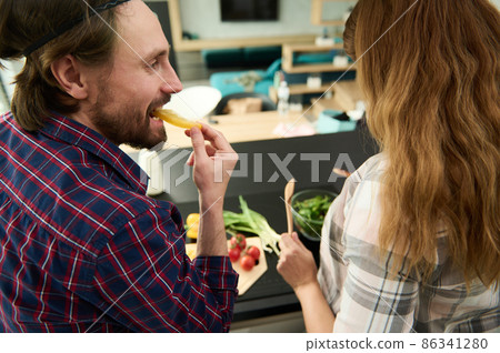 Rear view of a handsome Caucasian loving heterosexual couple preparing healthy meal together in the kitchen island 86341280