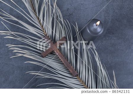 Catholic Cross with palm leaf and burning candle. Ash Wednesday, Lent season, Holy Week, Good Friday and Palm Sunday concept. Catholic Cross with palm leaf and burning candle. Ash Wednesday, Lent season, Holy Week, Good Friday and Palm Sunday concept. 86342131