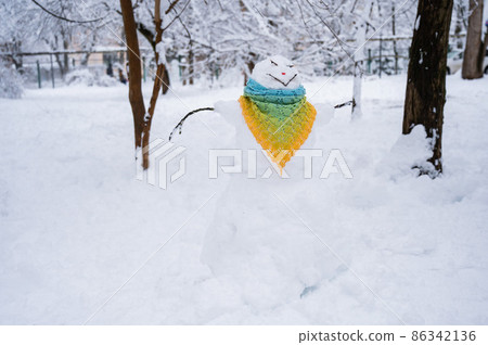 Snowman dressed in a crocheted scarf. Winter fun. 86342136