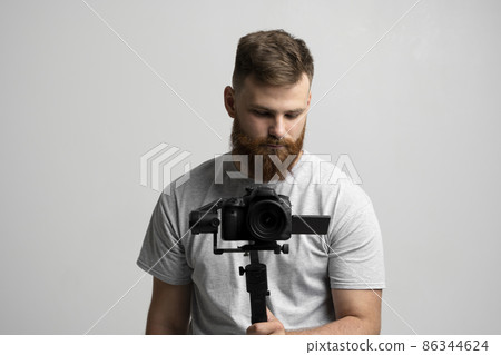 Bearder videographer with 3-axis gimbal and dslr camera. Filmmaking, videography, hobby and creativity concept. Bearder videographer with 3-axis gimbal and dslr camera. Filmmaking, videography, hobby and creativity concept. 86344624