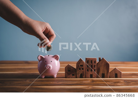 Money Savings for Future Property House Concept, Hand is Putting Coin Into Piggy Bank for Saving Future Housing Real Estate Ownership. Banking Fund for Investing House Asset and Real Estate 86345668