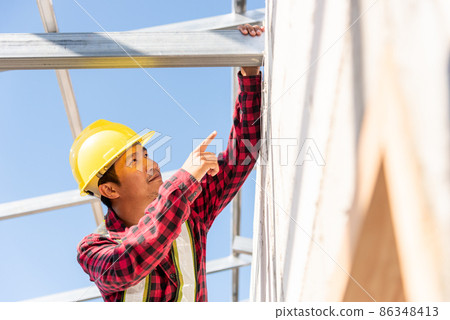 Construction worker or contractor checking house frame Construction worker or contractor checking house frame 86348413