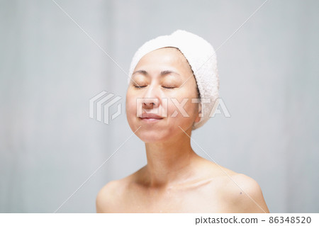 一個真臉的中年婦女，她用毛巾裹著頭，閉上了眼睛 86348520