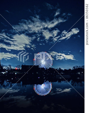 冬季夜空清澈，白雲飄揚的公園池塘水面上反射的摩天輪 86350382