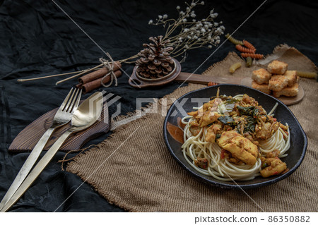 Spaghetti topped with Stir fried spicy snapper on a brown plate Served with Crispy butter toast. 86350882