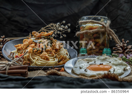 Spaghetti topped with Stir fried spicy snapper on a brown plate Served with Fried Egg. Spaghetti topped with Stir fried spicy snapper on a brown plate Served with Fried Egg. 86350964