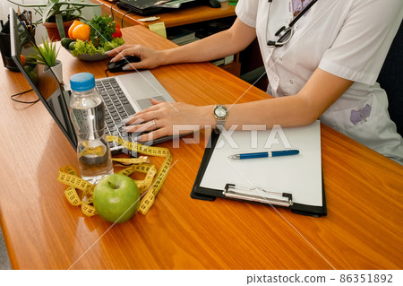 Woman dietitian with tape measure working on a diet plan. Weight loss Woman dietitian with tape measure working on a diet plan. Weight loss 86351892
